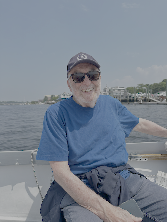 photo of Maurice J. "Mitch" Freedman on a boat on water, wearing a blue shirt, sunglasses, and a ball cap